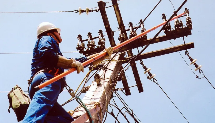 Ilustrando o desligamento programado, agente de serviços da Copel realiza manutenção em um poste de energia elétrica.
