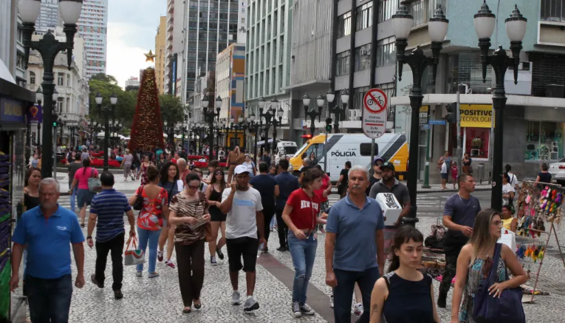 A foto mostra pessoas andando no centro de Curitiba