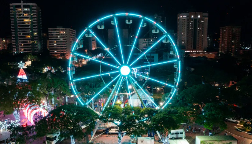 A foto mostra a roda gigante e o túnel de luz da Maringá Encantada acesos.