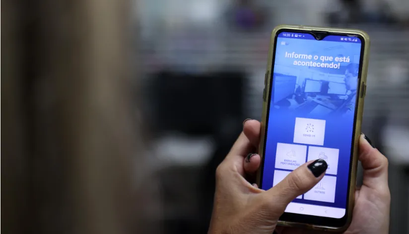A foto mostra uma mão segurando um smartphone com o aplicativo 190 PR aberto na tela.