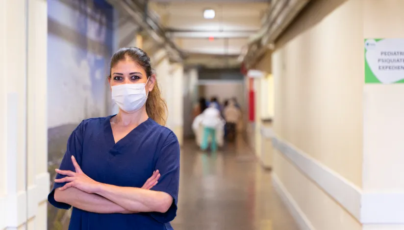 A foto mostra uma médica em um corredor de hospital.