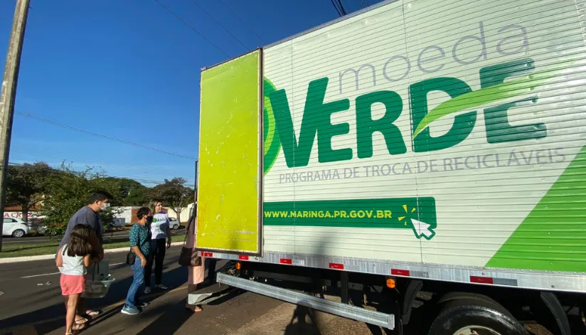 Caminhão do projeto Moeda Verde recebe moradores com sacos de lixo reciclavel para troca por alimentos.