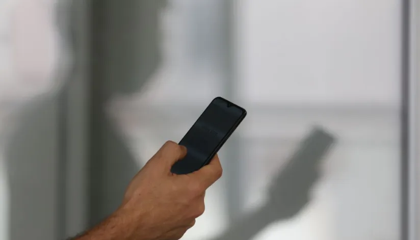 A foto mostra uma mão segurando um celular.