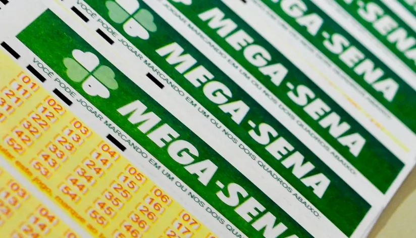 A foto mostra cinco bilhetes a mega-sena sobrepostos um sobre o outro.
