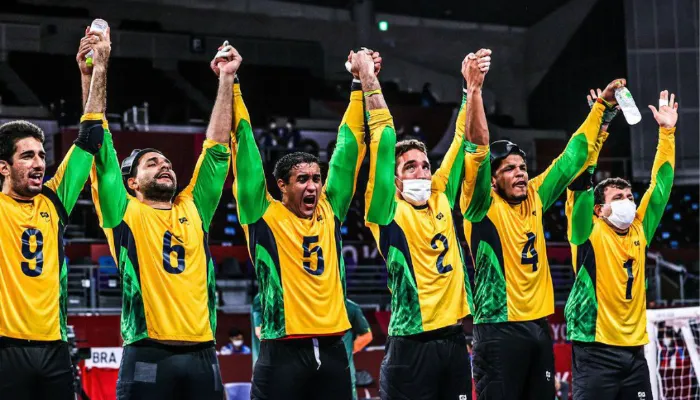 Na foto, os jogadores da seleção comemoram a conquista do ouro em fila, lado a lado, de mãos dadas para cima.